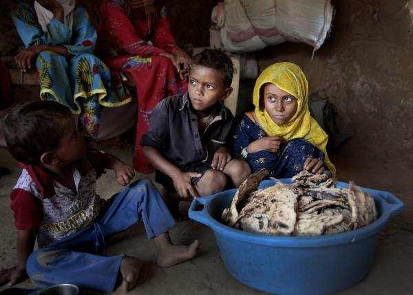 Children sit around moldy bread at shelter in Yemen.