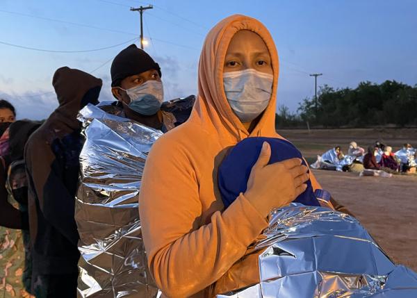 Mother holds her 9 year old as they wait for Border Patrol to take them into custody.