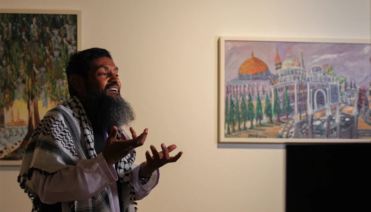 Ahmed Rabbani gestures while speaking with journalists during the exhibition of his artworks at IVS art gallery in Karachi.  Photo by Hassaan Ahmed