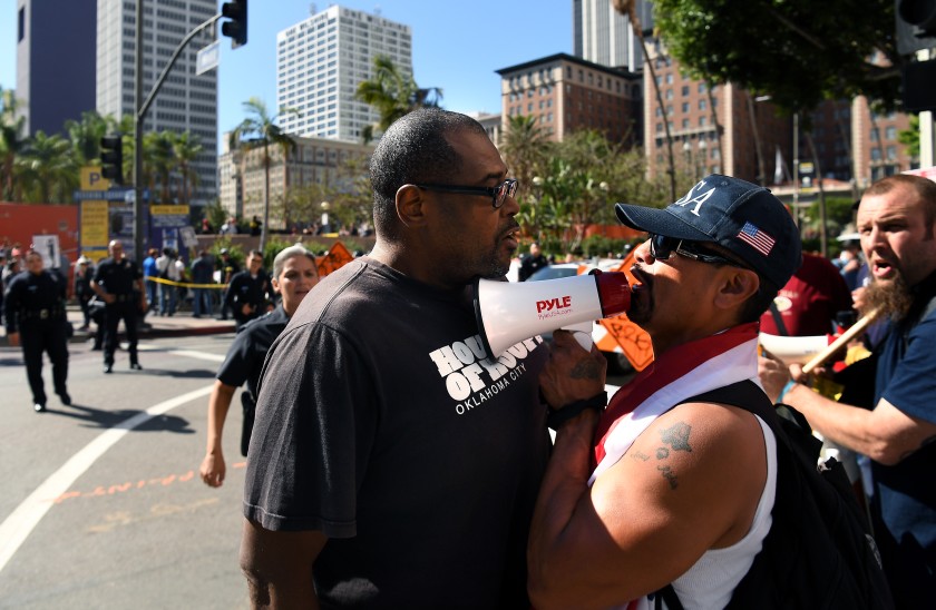 A Trump supporter holds a small bullhorn to his mouth  while standing chest to chest with an anti-Trump protester