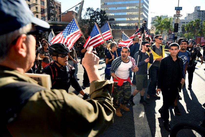 Trump supporters march as an anti-Trump protester yells