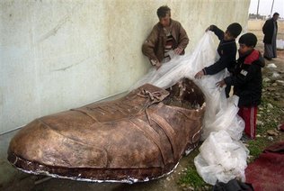 Varios nios desenvuelven una escultura creada como un monumento a los zapatos que un periodista iraqu arroj en diciembre al entonces