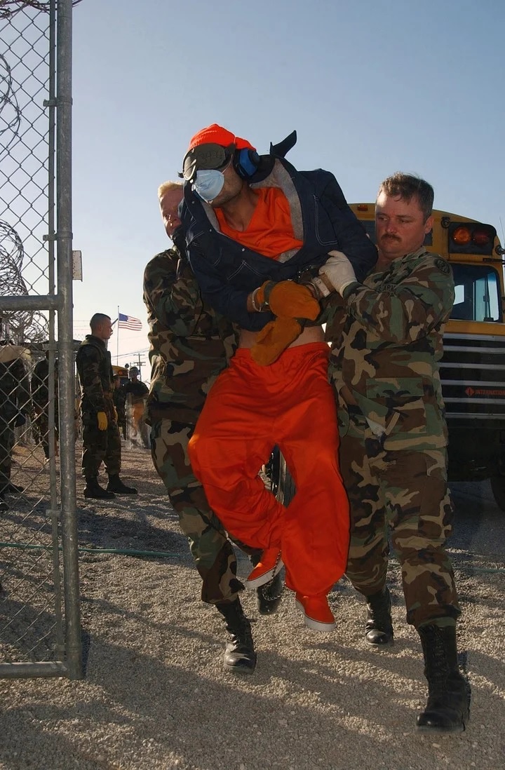 La polica militar levanta a un preso annimo de un autobs a un sitio de procesamiento en el centro de detencin Camp X-Ray,Foto Sargento de Estado Mayor Jeremy T. Lock va The New York Times.