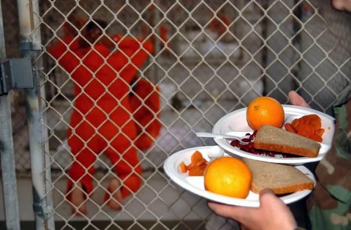 Los detenidos reciben comidas a base de arroz, porotos, zanahorias y naranjas en el Campamento X-Ray, Foto Suboficial de primera clase Shane T. McCoy/Marina de los EE. UU. va The New York Times.