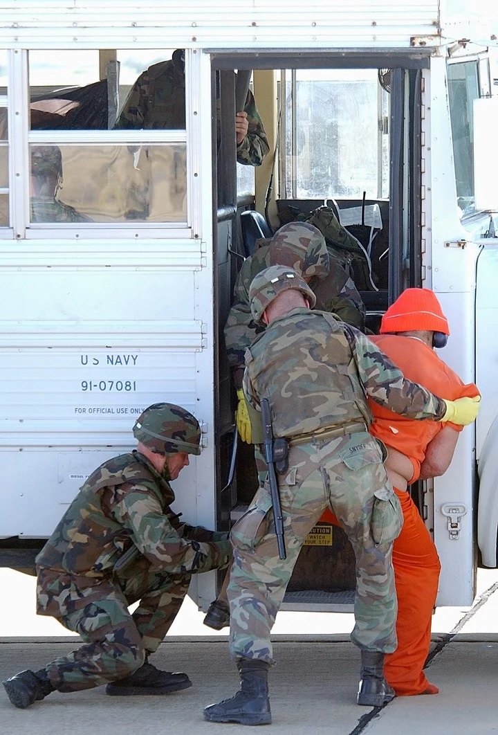 Marines cuestodiando de a dos a un prisionero. Foto Sargento de Estado Mayor Jeremy T. Lock va The New York Times.