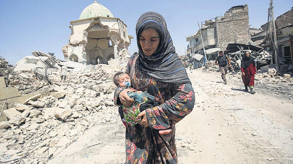 Una mujer camina con su beb delante de las ruinas de mezquita de Al Nuri, en el oeste de Mosul.